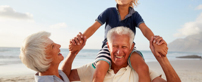 A senior couple playing with their granddaughter at the beach
