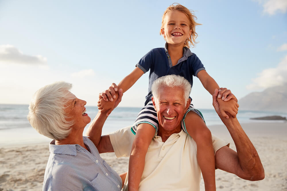 A senior couple playing with their granddaughter at the beach