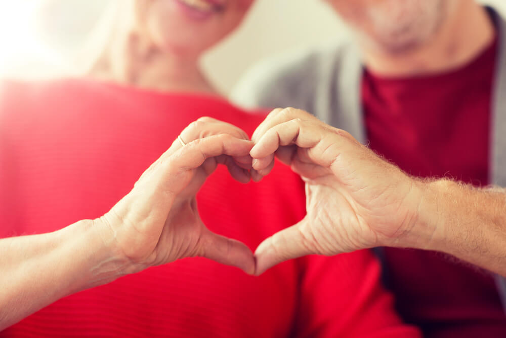 A senior couple making a heart shape with their hands