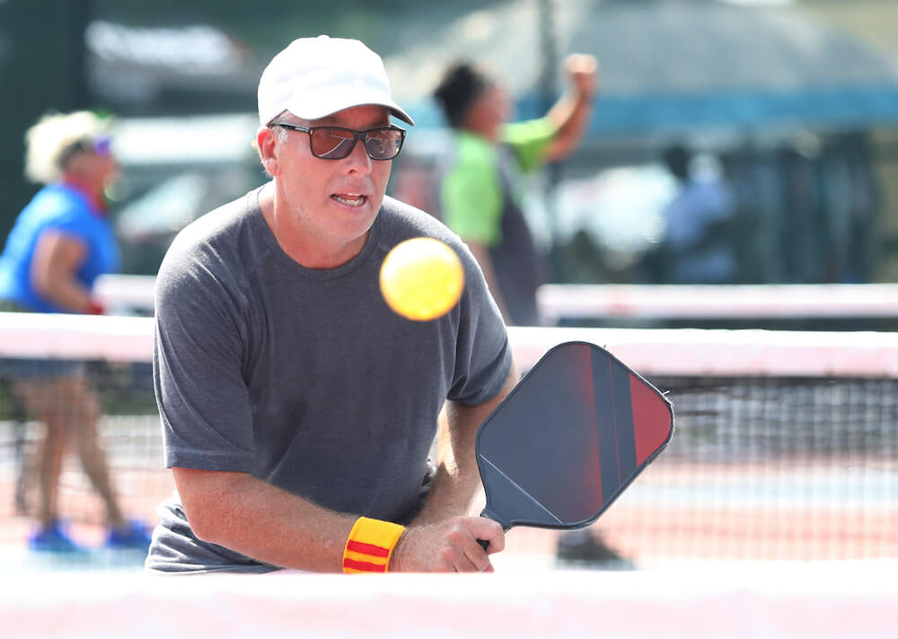 A senior man playing pickleball at his luxury independent living community