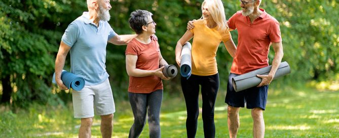 Group Of Happy Senior People Making Sport Training Together Outdoors, Cheerful Elderly Men And Women Walking In Park With Fitness Mats In Hands, Laughing And Enjoying Outside Workout, Full Length