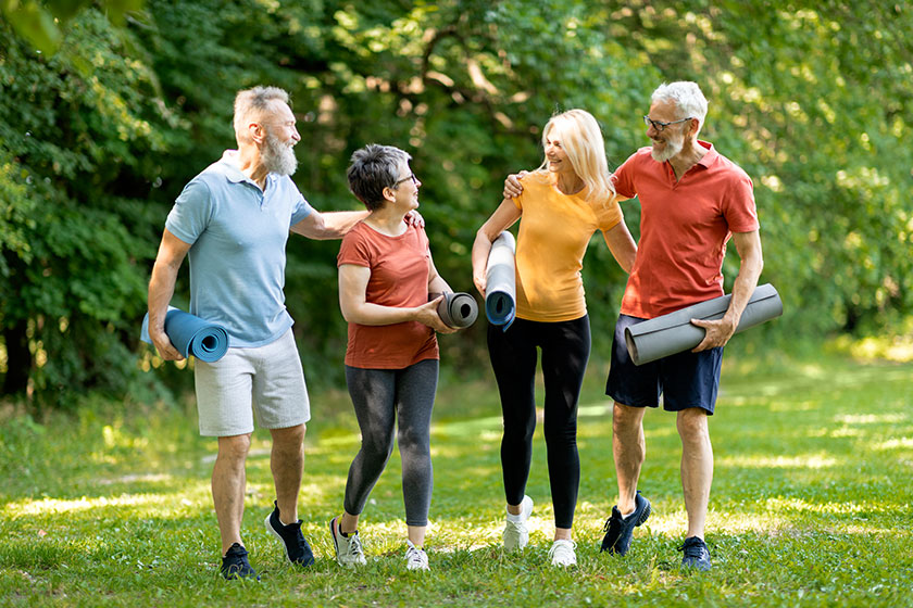 Group Of Happy Senior People Making Sport Training Together Outdoors, Cheerful Elderly Men And Women Walking In Park With Fitness Mats In Hands, Laughing And Enjoying Outside Workout, Full Length