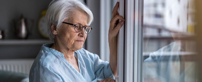 Senior woman looking out of window at home